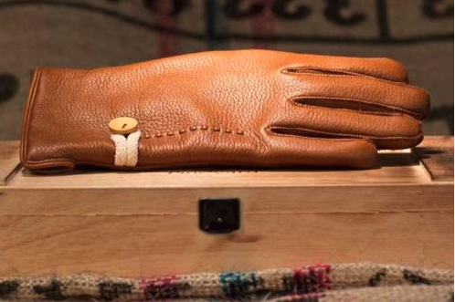 A brown glove on a wooden surfaceDescription automatically generated